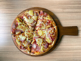 Top view of pizza tray on wooden table background. it is an Italian fast food consisting of a flat round dough topped with tomato sauce. Then cooked by baking in the oven.