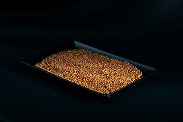 Buckwheat lies on  black-blue background on a black long flat plate Ukrainian culture light protein...