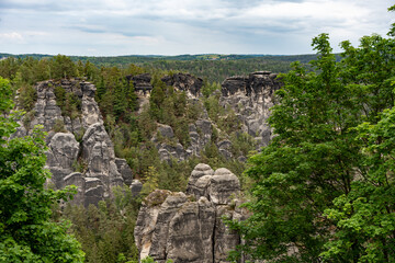 A mountain range with a forest in the background. The trees are green and the sky is cloudy