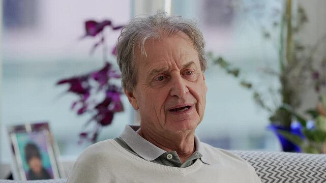 Close-up of a grandfather smiling warmly while sitting on the couch, capturing the genuine happiness and contentment of a peaceful moment at home