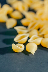 close up yellow vermicelli in the shape of shells lies on black and blue background Ukrainian culture the result of flour processing Italian cuisine