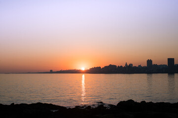 Naklejka premium Sunset in the city with orange reflections in the sea.