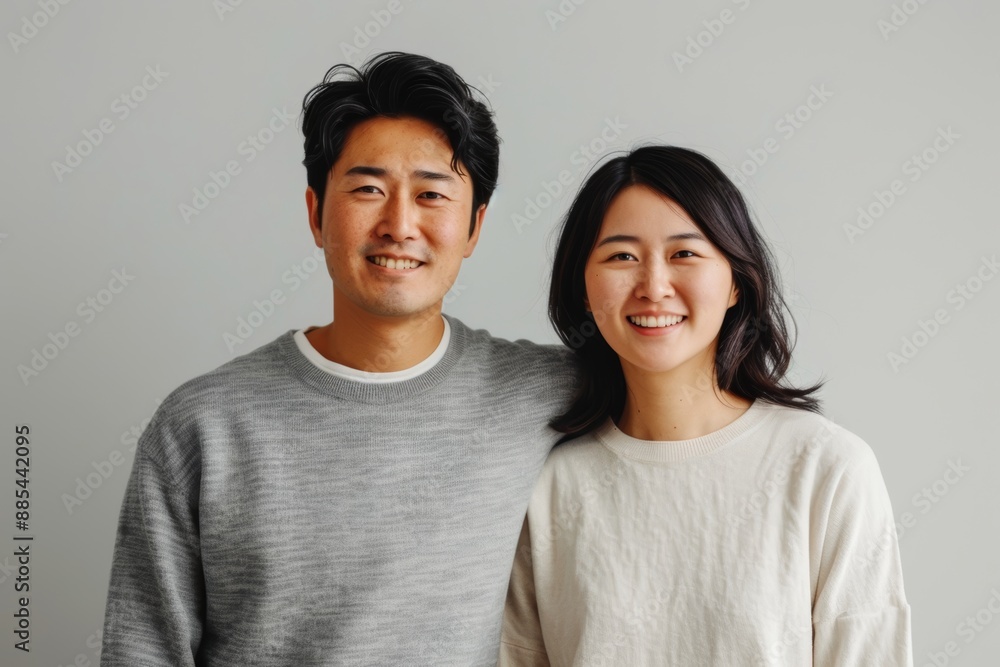 Wall mural Portrait of a content asian couple in their 30s showing off a lightweight base layer on minimalist or empty room background