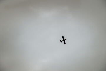 Light aircraft in sunlight on dark clouds. Airplane flying under cloudy sky. Planes flying high in the sky with heavy clouds.