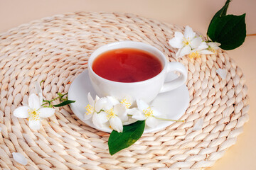 A cup of jasmine tea on a wicker place mat with jasmine flowers. Top view
