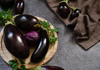 Fresh mini eggplant in a wooden plate on a white wooden background. Vegetables.