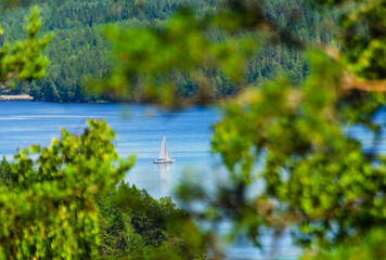 Aerial view of lake in Finland from a hill. A small boat traveling in the lake surface at summer time. Romantic vacation feelings near Himos and Jyväskylä Säynätsalo. Nice tourist spot. 