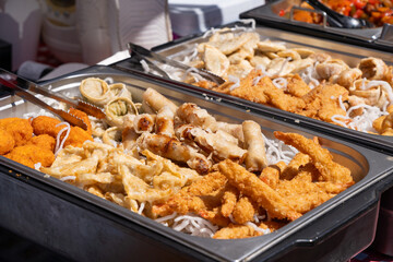 Fried Asian snacks on display, featuring crispy onion rings, tempura shrimp, and assorted dumplings