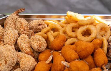 Fried Asian snacks on display, featuring crispy onion rings, tempura shrimp, and assorted dumplings