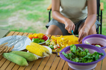 Close-up of asian girl cutting fresh vegetable in bowl.