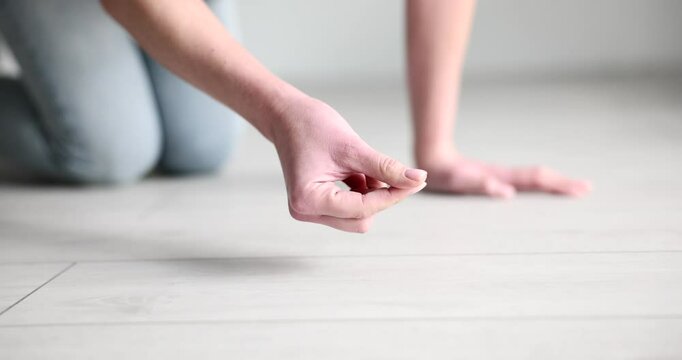 Housewife collects dust on laminate floor with finger. Woman swipes finger on flooring trying to check need for cleaning apartment slow motion