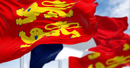 Flags of Normandy and France waving in the wind on a clear day
