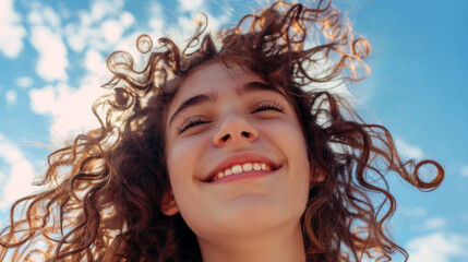 Close up portrait of a brunette  happy, smilling teenage girl with curly hair against the blue sky background. Happy and successful life concept. Selective focus. Generative AI.