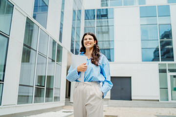 One beautiful young successful business woman going to work at business office modern building while holding papers and wearing glasses	