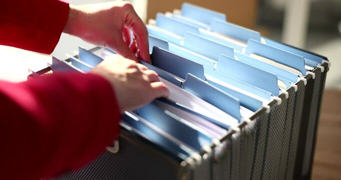 Woman seeks file in card index box in corporate archive. Office worker checkups documents to find contract. Organized paperwork system at company