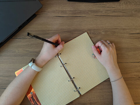 top view of woman writing in notebok on wooden table