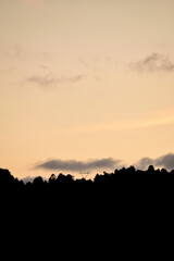 Atardecer anaranjado en cielo oscuro sobre la silueta de la montaña