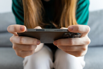 The girl is playing on her phone. The girl is working at the phone. Close-up