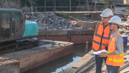 Fototapeta premium Construction engineer working on a bridge construction site over a river,Civil engineer supervising work,Foreman inspects work at a construction site,Discuss technical problems together
