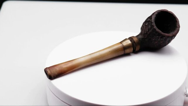 4k video of an ancient wooden pipe for smoking tobacco, which rotates on itself on a white background
