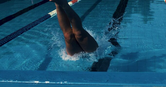 Super slow motion of young professional female swimmer with cap and goggles swimming with passion and motivation to achieve a victory in competition while practicing in swimming pool.