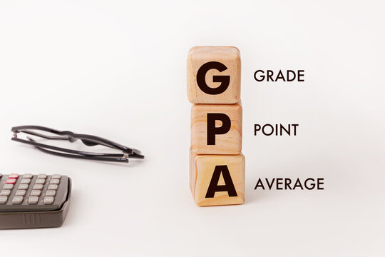 Three wooden blocks with text GPA symbolizing the concept of Grade point Average with glass and calculator on table