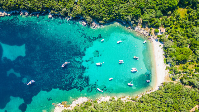 An aerial view of the Blue Lagoon at Plaža Kru&scaron;ćica and Tarej Beach on the island of Cres, showcasing their fantastic turquoise waters and surrounding islands. Boats dot the serene lagoon