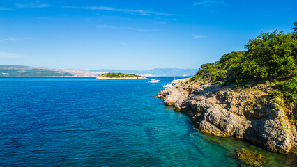 An aerial view of Plavnik and Mali Plavnik islands, captured by drone, with a boat sailing nearby. These picturesque islands are located close to Cres and clear blue water