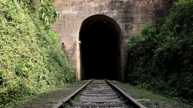 homem saindo t&uacute;nel caminhando sobre estrada de ferro