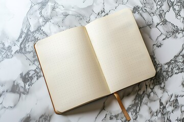 A minimalist composition featuring an open blank notebook resting on a marble surface