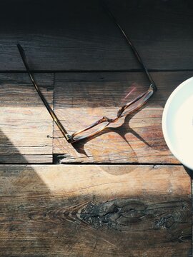 glasses on sunny wooden table with shadows and coffee
