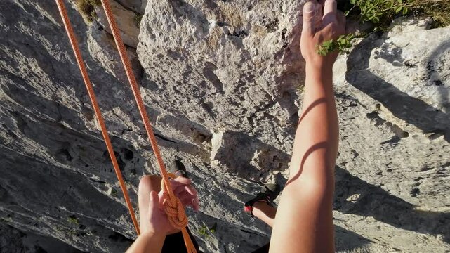 POV of rock climber rappelling down a tall rock face. High quality 4k footage