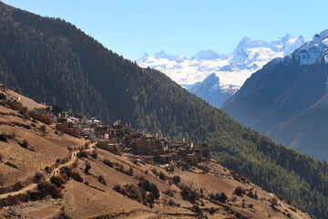 View from the trail to Manang back to the village of Ghyaru in front of the snow capped peak of Mount Lamjung Kailas, Himal, Annapurna Circuit Trek, Nepal