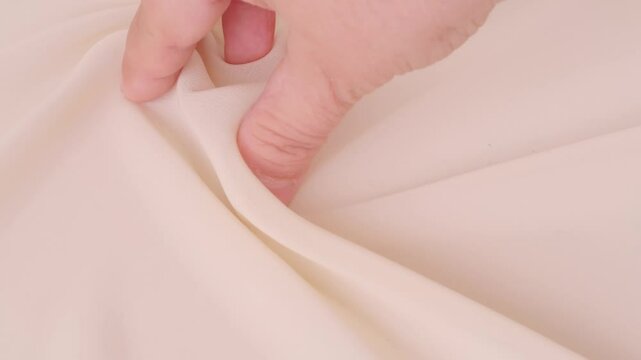 Female hands inspecting silk texture and quality delicate chiffon, crepe, hand feels sensual tactile pleasure, testing for durability, stretch and crease resistance