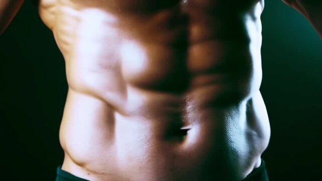 Strong athletic man showing muscular body and six pack abs on black background. Sexy naked torso, six pack abs. Male flexing his muscles. Close up on perfect abs. Strong bodybuilder with six pack. 4k 