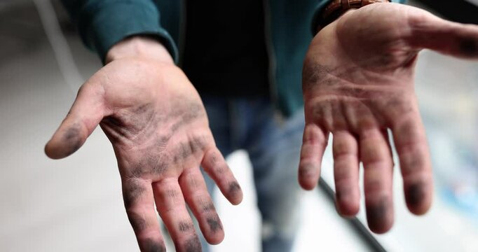 Man tries to shake dust off hands showing dirty palms. Male person with grime stands in living room in process of renovation slow motion