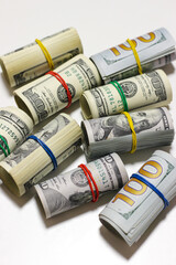 Hundred dollar bills rolled up with colorful rubber bands, isolated on white background