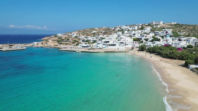 Beautiful aerial view of Donousa, Greece. Turquoise water meets white sand beach, charming village on hill, blue sky. Idyllic scene