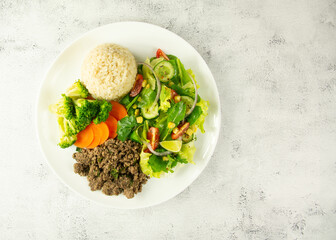 Savory ground beef with steamed broccoli, carrots, brown rice, and a vibrant mixed green salad.