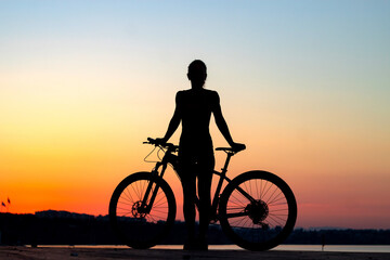 . | outdoor pursuit. healthy lifestyle concept. sunrise sunset silhouette of a woman with a bicycle