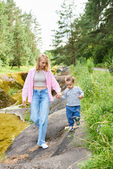 Fototapeta premium Motherhood concept. Mother and child explore nature while walking