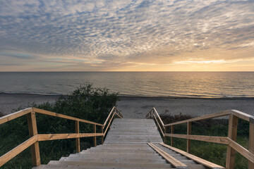 Obraz premium Wooden stairs leading down to the beach at the coast of Baltic sea in at sunset