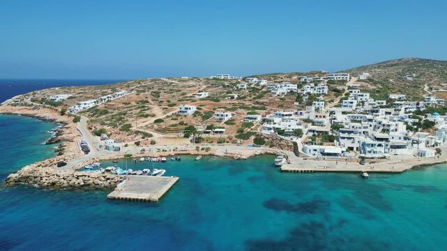 Aerial view of Donousa Island, Greece. Small harbor with boats amidst whitewashed buildings and scenic coastline. Turquoise waters surround the island