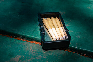 pre rolled marijuana joints in a metal box outdoors on a table