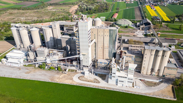 Mannersdorf, Austria - April 30, 2023: Huge cement factory surrounded by agricultural fields and beautiful natural landscape
