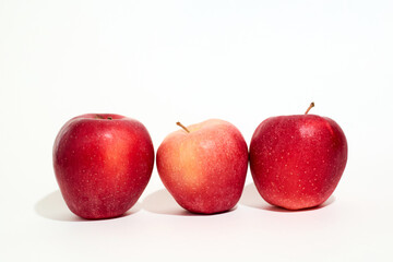 Three Red Apples Arranged Neatly on White Surface
