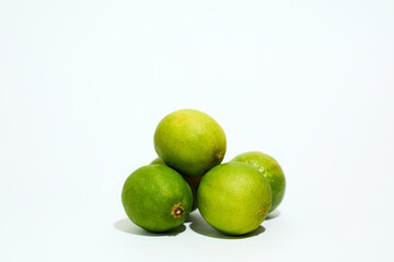 Three Limes Stacked on White Surface