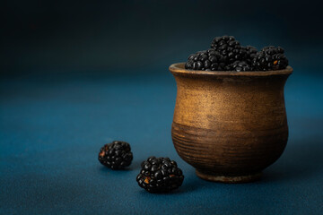 Blackberries in a clay jar. Ripe and tasty black berry close-up.