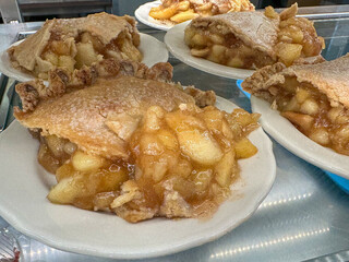 Slices of apple pie with double crust on white plates