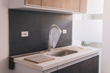 Modern kitchen in the process of being constructed with an unfinished countertop and uninstalled...